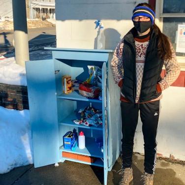 		Person standing next to an outdoor food cupboard
	