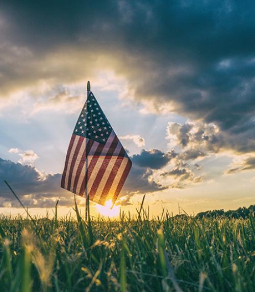 		 Small American flag backed by sunset
	