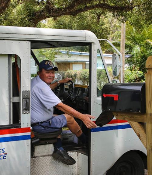 		 Person in blue uniform opening a mail box
	