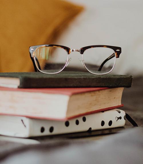 		 Eye-glasses on top of a stack of books
	