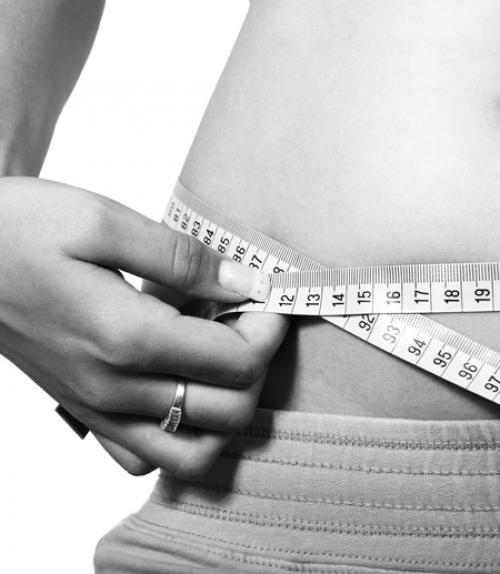 		 Woman measuring waist with tape measure
	