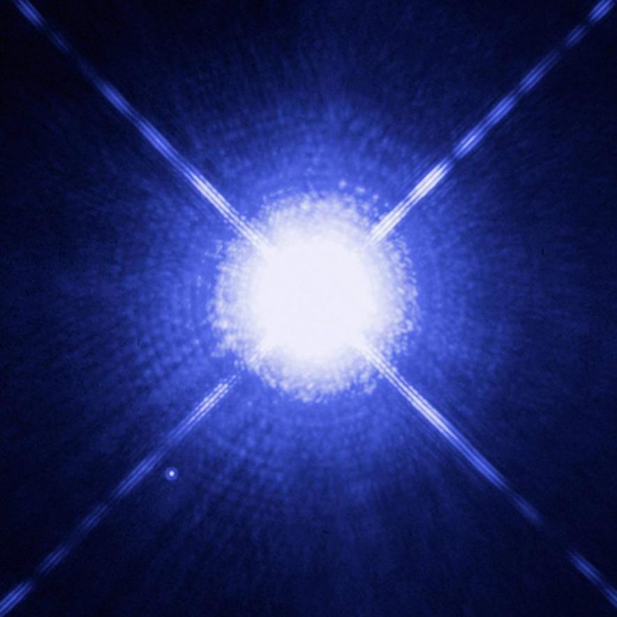 		Four lines of light radiating out from a white dwarf star on a blue background.
	