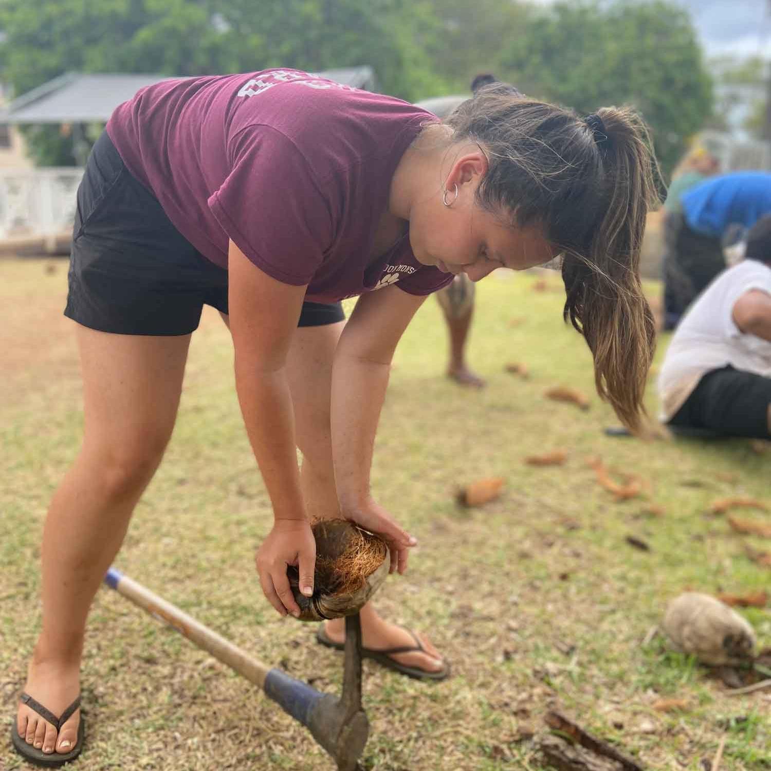 		woman husking a coconut
	