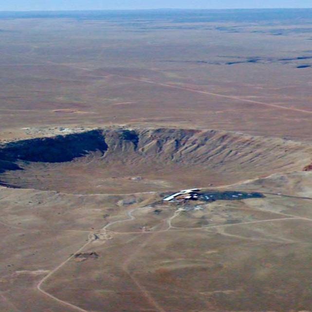 		Desert land seen from above, showing a huge crater
	