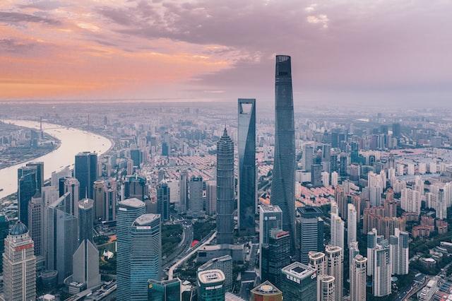 		A city of countless skyscrapers with a wide river off to the left and an orange sunrise in the sky. 
	