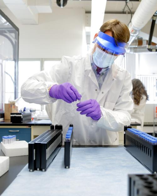 		Person wearing protective lab gear handles virus test samples
	