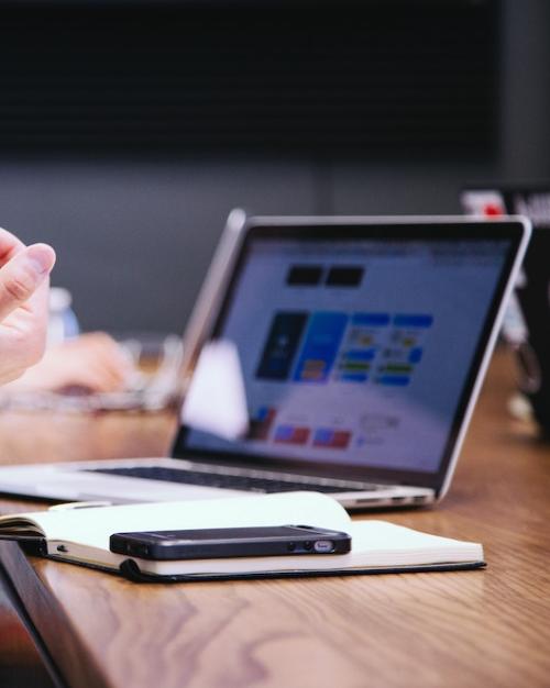 		Hands gesturing in front of a laptop computer and a notebook
	