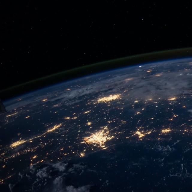 View of Earth from space: dark blue with spots of yellow light