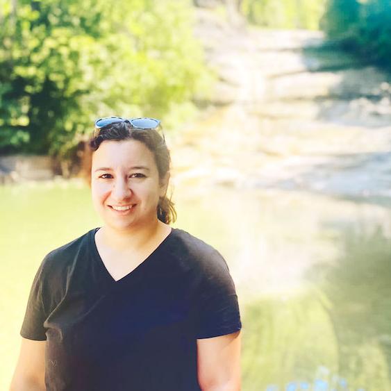 Person in front of a pool of water surrounded by stone banks