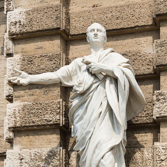 light colored stone statue of a person in a toga, speaking