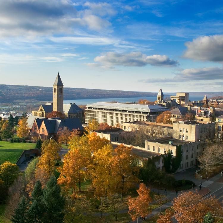 Cornell campus seen from above in autumn, with Cayuga Lake in the distance