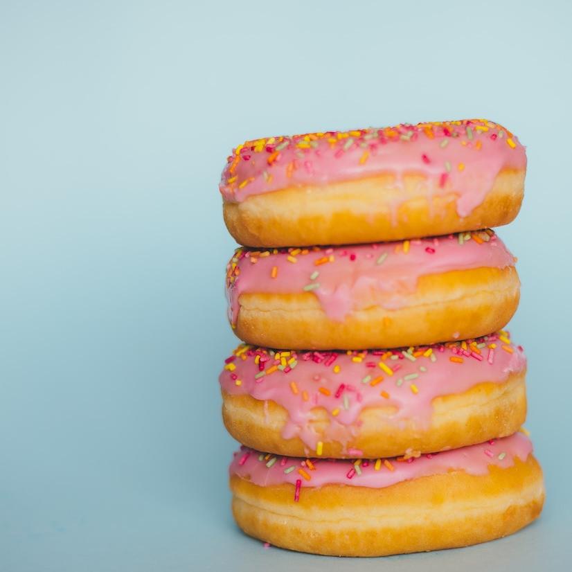 		Four donuts in a stack: frosted pink, covered with sprinkles
	