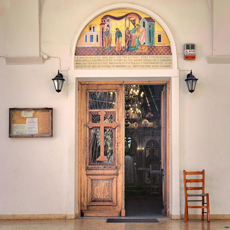 		Doorway decorated with a wooden cross and colorful painting of four figures
	