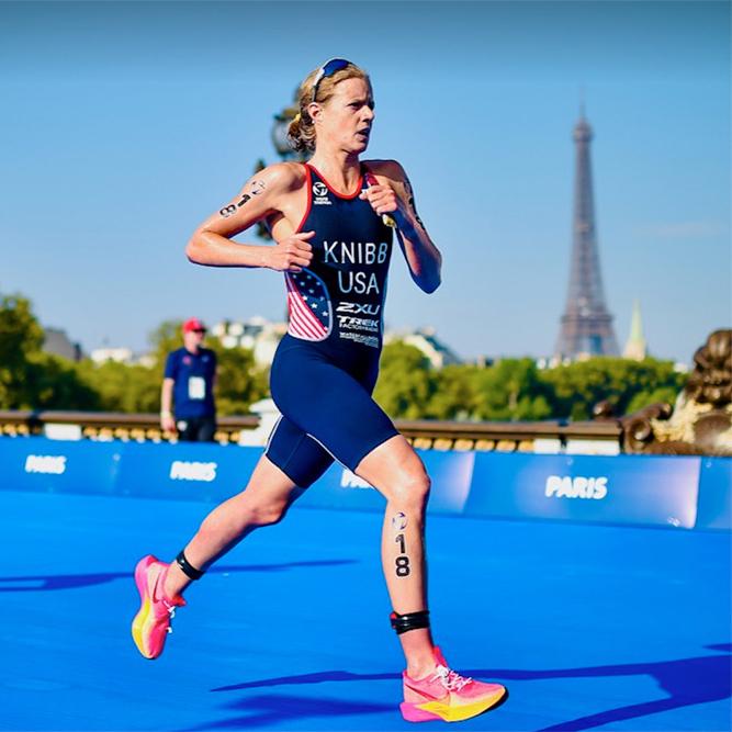 Person in racing gear runs on a blue pathway with the Eiffel Tower in the background