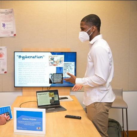 		Two people converse over a table, with a computer screen at one end
	