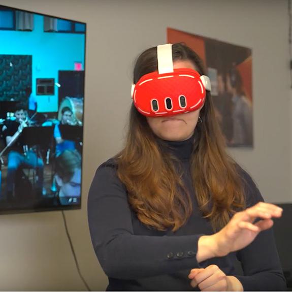 		Person wearing a red virtual reality headset and gesturing with her arms
	
