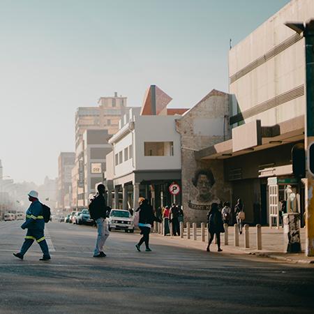 People crossing a wide city street under a clear sky