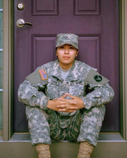 Person wearing fatigues sitting on a porch