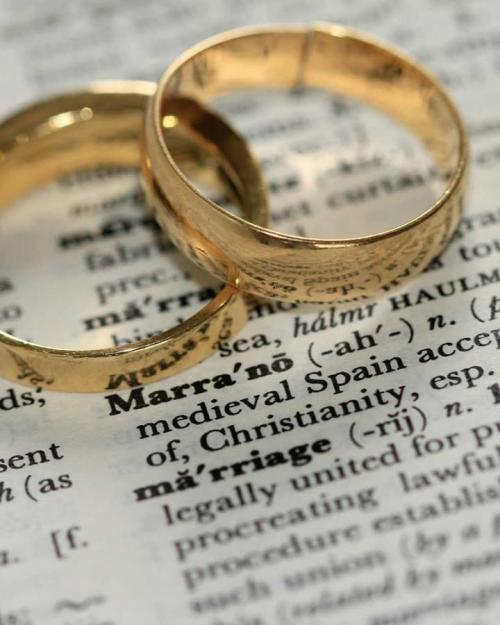 Two gold rings on a dictionary definition of 'marriage'