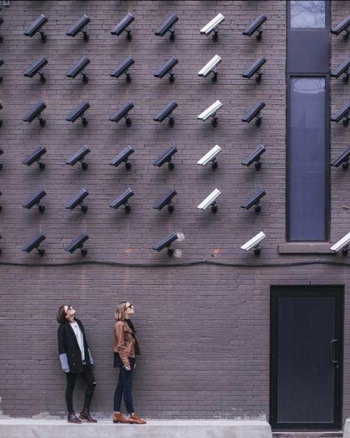 Two people face many security cameras