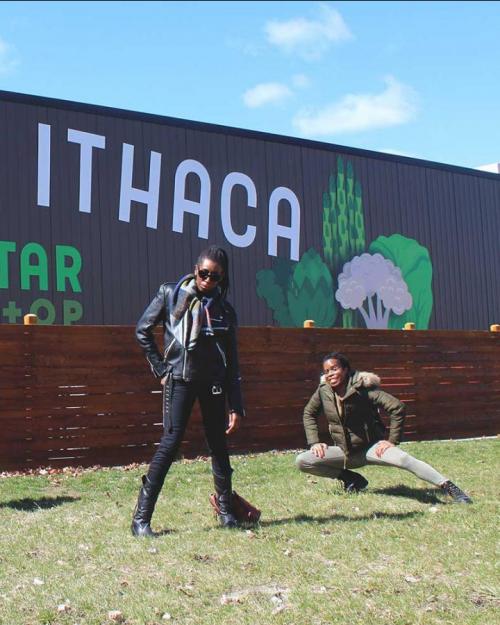 Four people pose in front of a building painted with vegetables