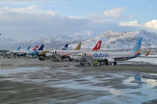 Planes in a row with snow-covered mountains behind them.