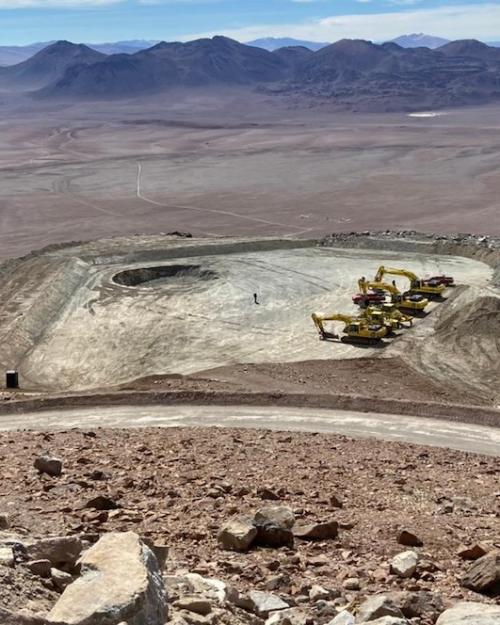 Flat ground and four construction vehicles; mountians in background