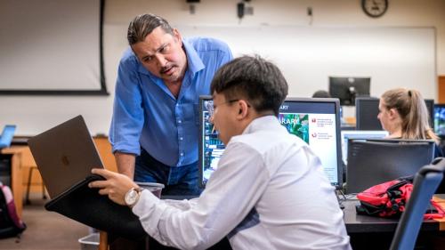 Mark Sarvary looking at a student's computer during a class.