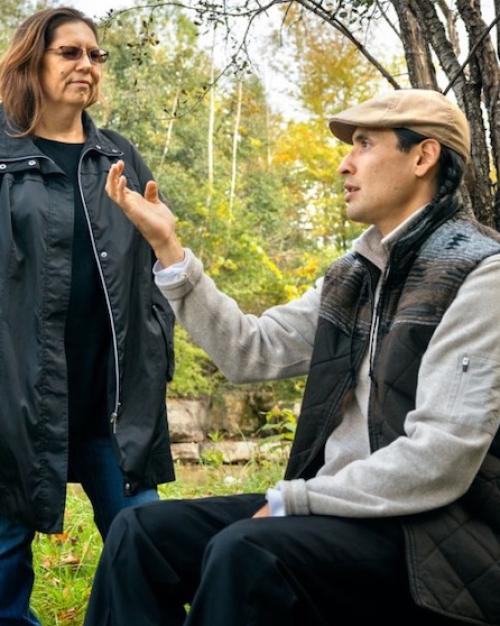 Two people talking in a wooded setting