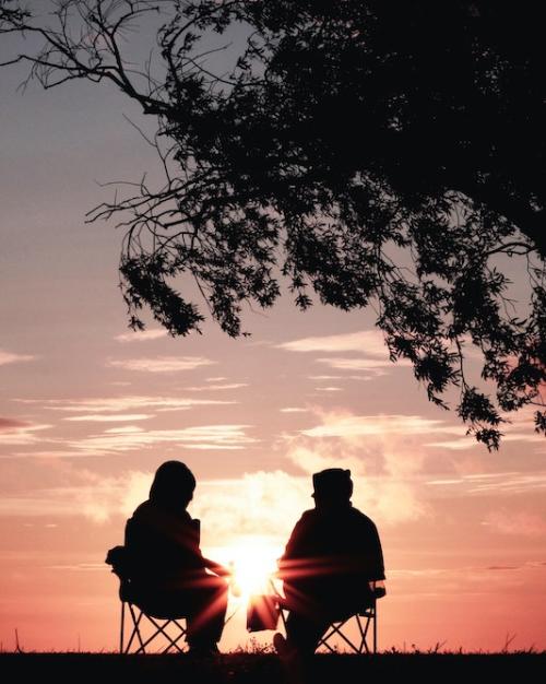 Two seated figures sillhouetted against a red sky