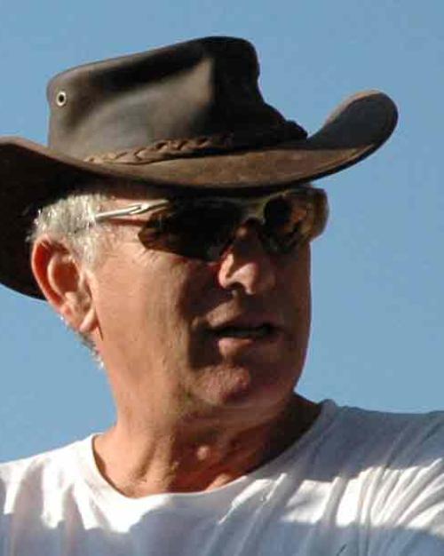 White-haired Aviam wearing a leather cowboy hat, wearing sunglasses and a white t-shirt.