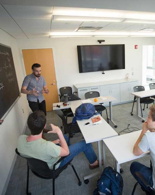 Person speaks in front of a class sitting using dynamic hand gestures