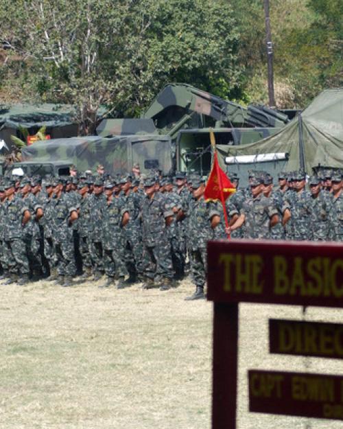 Soldiers stand in formation beyond a wooden sign