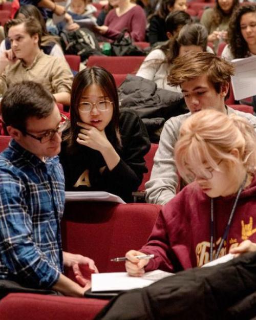 Four people confer over notes