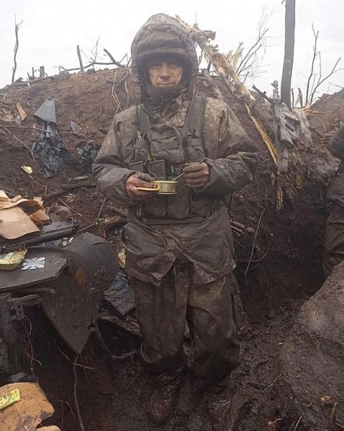 Solder wearing battle-worn clothing, eating out of a cup