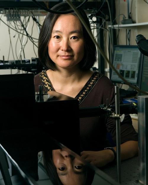 Michelle Wang, next to a microscope and with dangling wires and equipment behind her