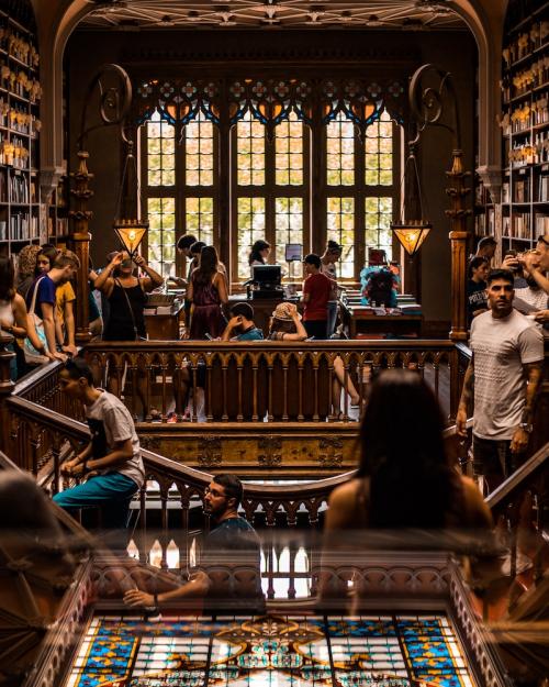 Library room with tall, ornate windows, crowded with people