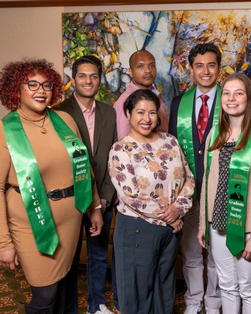 		Nine people pose; some wear green stolls
	