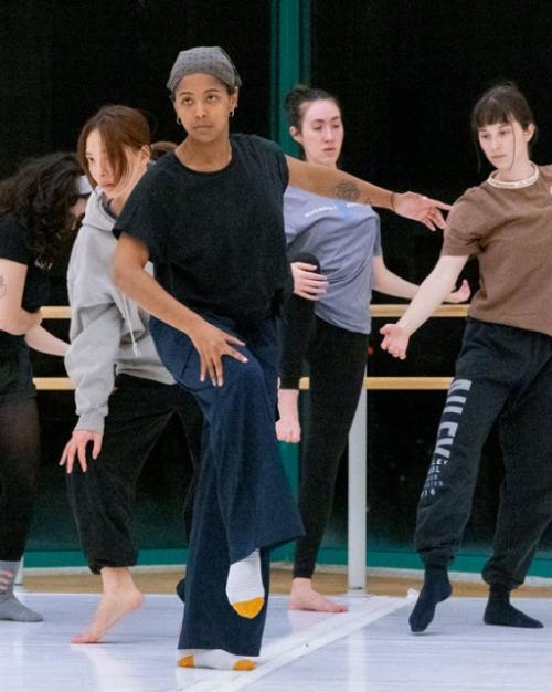 Five people perform a dance, creating a V formation with their bodies