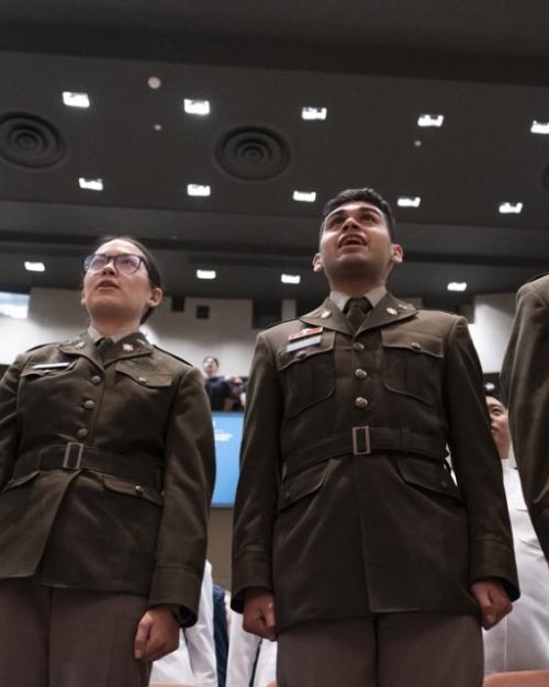 Five people in military uniforms stand at attention