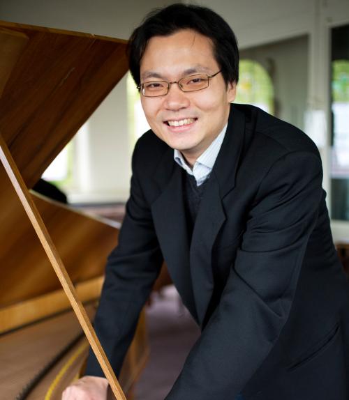  Photo of Mike Lee leaning against a piano