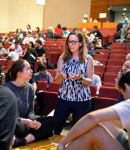  Instructor talks with a student in a lectur hall