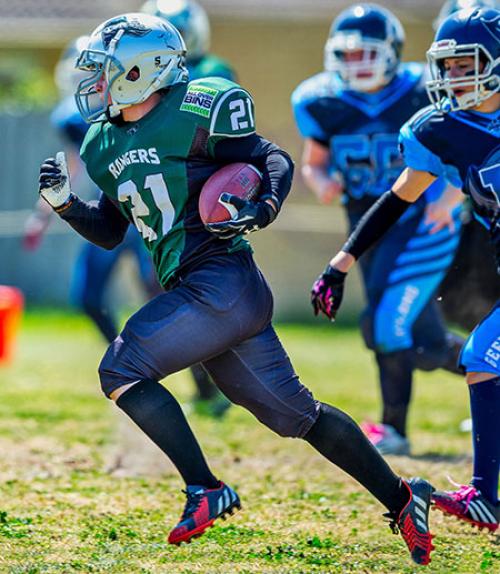  Football player running with the ball while chased by other team