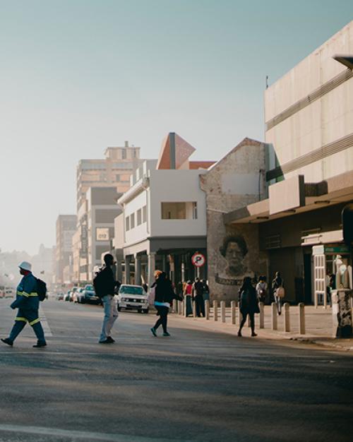 People crossing a wide city street under a clear sky