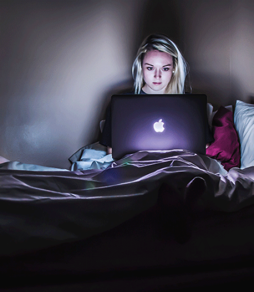  Woman in dark room gazing into computer screen