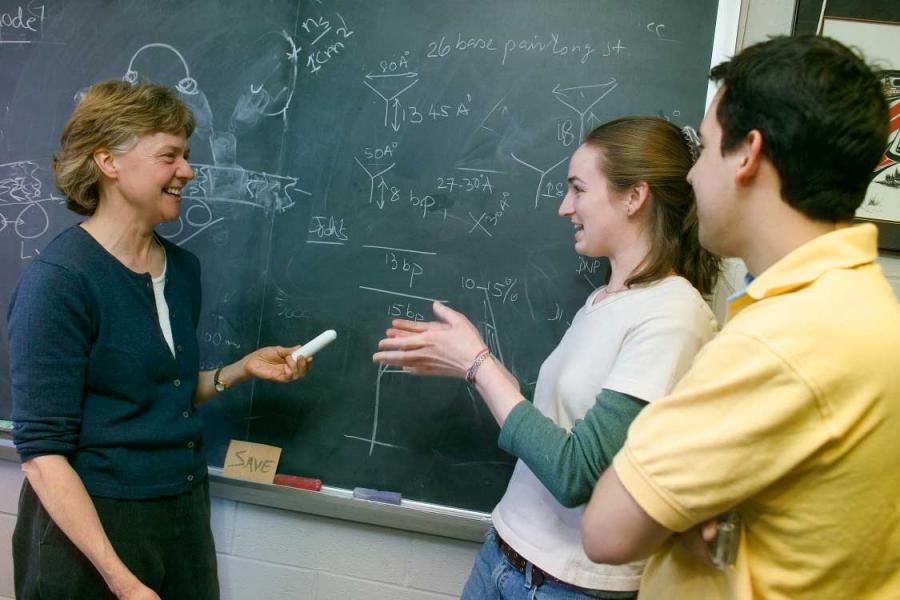 Three people in a classroom, laughing