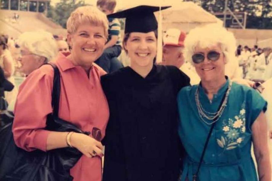 three women, one wearing graduation robes