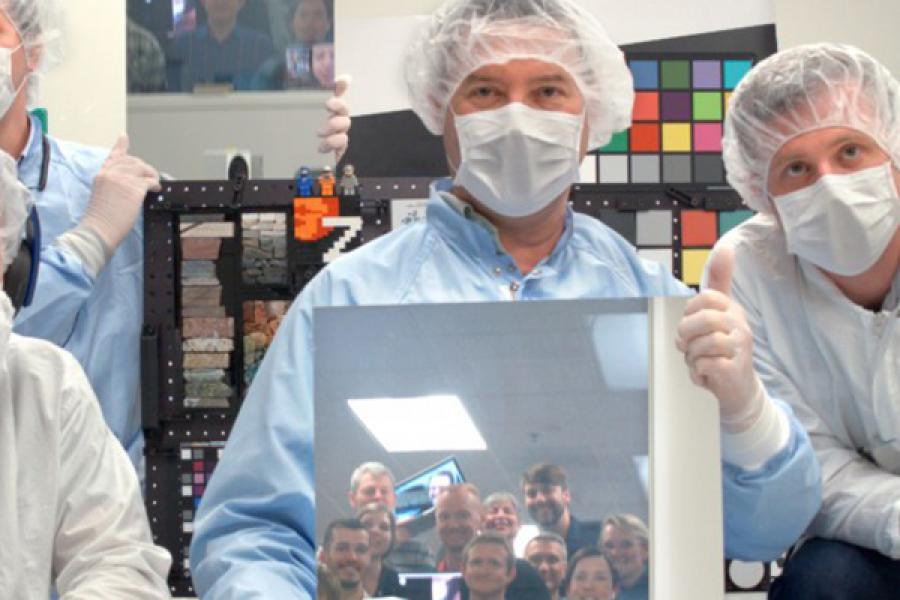 Two people in face masks and hair nets, in a lab