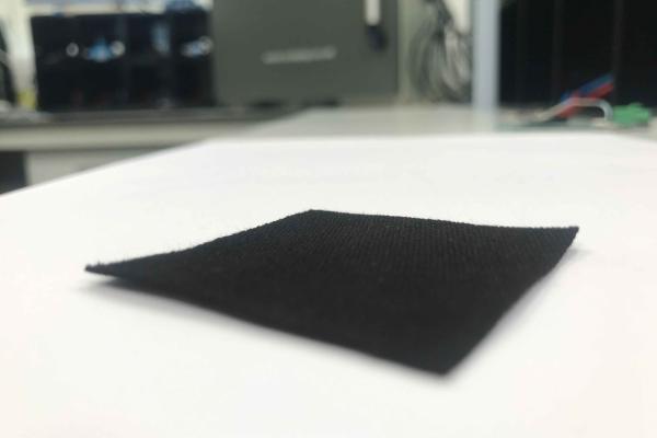 A square, thin sheet of black carbon on a tabletop