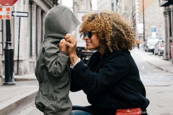 A mother helping a child with the hood of a parka